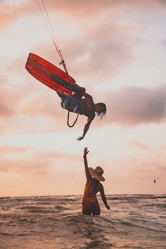 Silhouette of a man and woman kitesurfing at sunset, capturing the thrill of water sports.