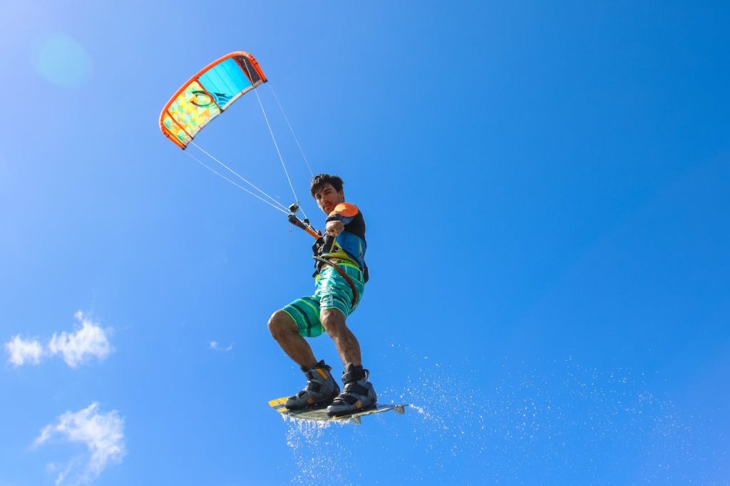 A thrilling kiteboarder performing stunts in the air with clear blue sky backdrop, capturing the essence of adventure and sport.